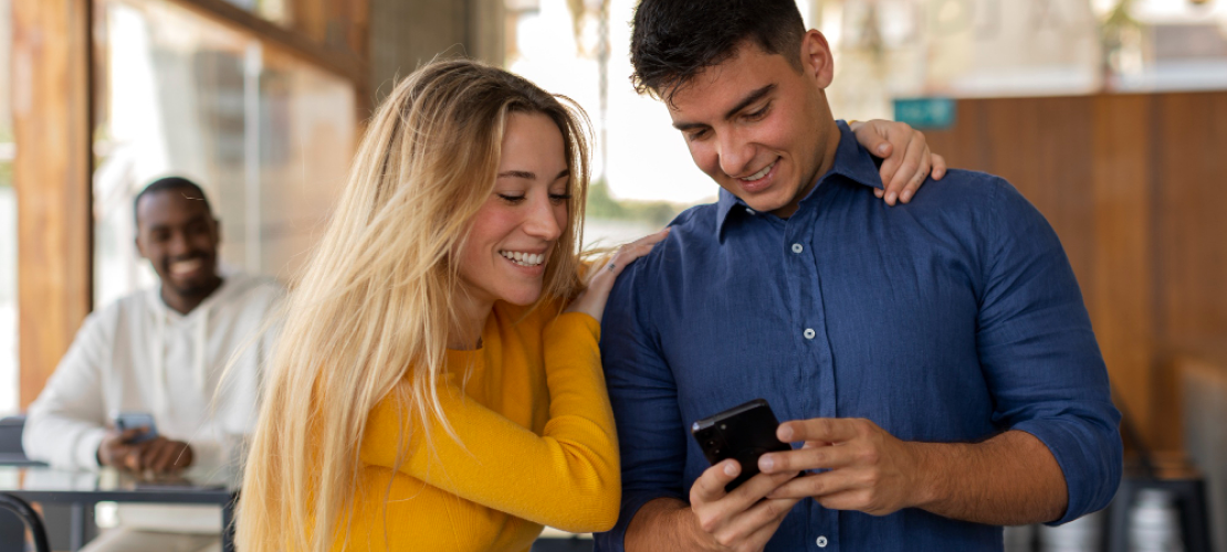 Two people smiling while looking at a phone.