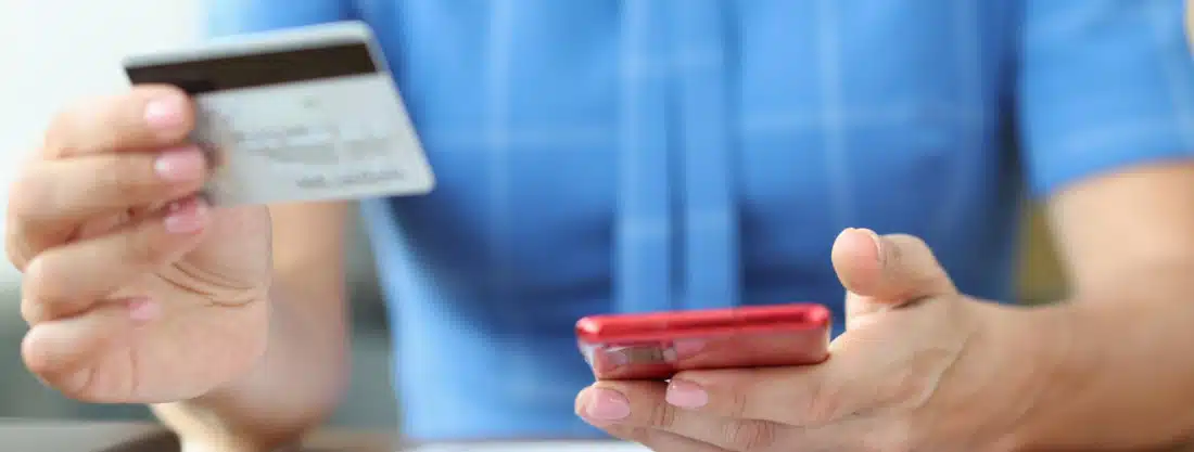 Image of person holding credit card and mobile phone